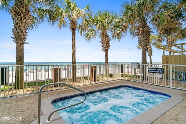 view of pool featuring a community hot tub, a water view, and fence