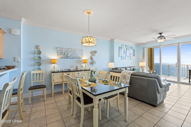 dining area with light tile patterned floors, ceiling fan, a water view, a textured ceiling, and crown molding