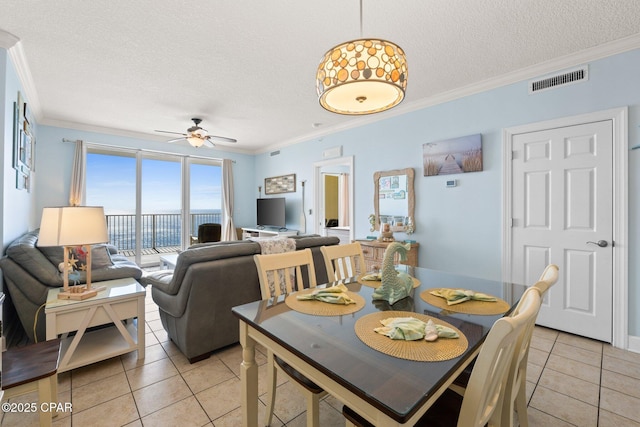 dining area featuring visible vents, a textured ceiling, light tile patterned flooring, and crown molding