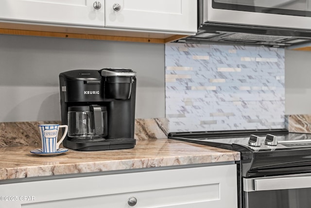 kitchen featuring light countertops, tasteful backsplash, white cabinets, and stainless steel range with electric cooktop