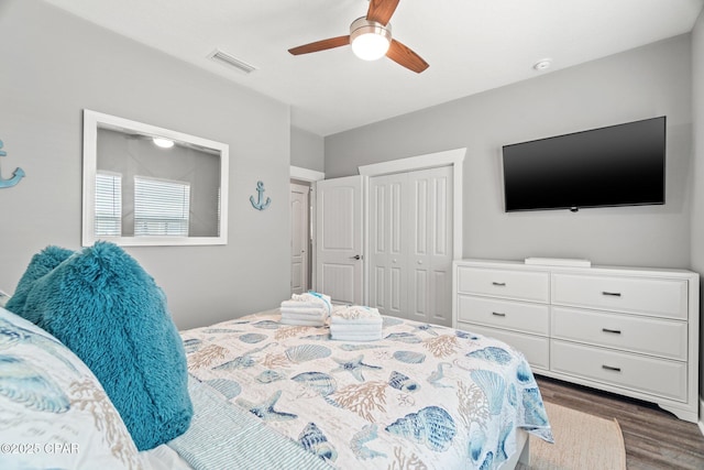 bedroom featuring ceiling fan, visible vents, dark wood finished floors, and a closet