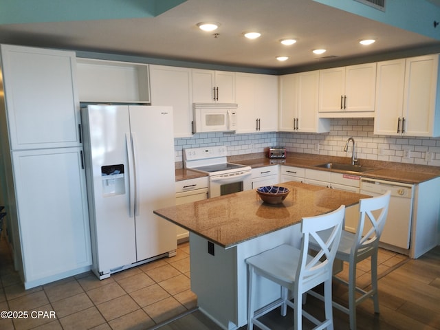 kitchen with white appliances, white cabinetry, backsplash, and a sink