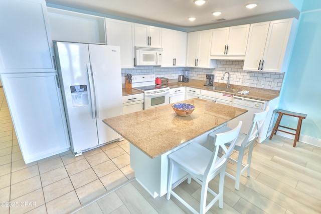 kitchen with a sink, white appliances, tasteful backsplash, and white cabinetry