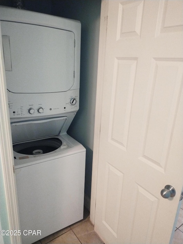 washroom featuring laundry area, stacked washer / dryer, and light tile patterned flooring