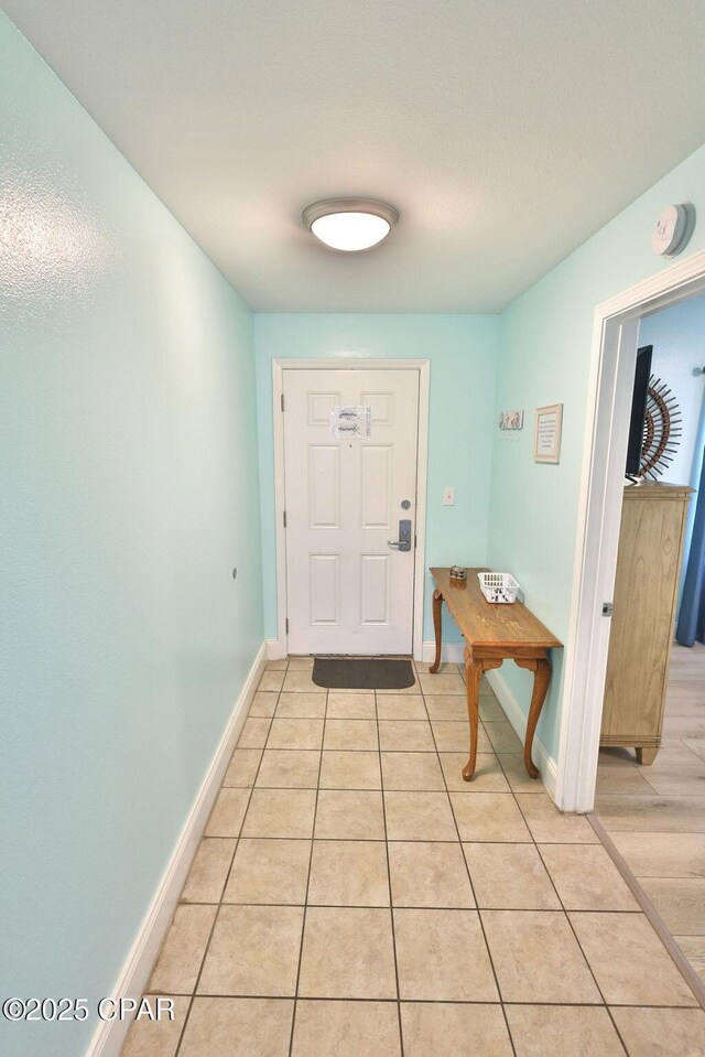 doorway to outside featuring light tile patterned flooring and baseboards