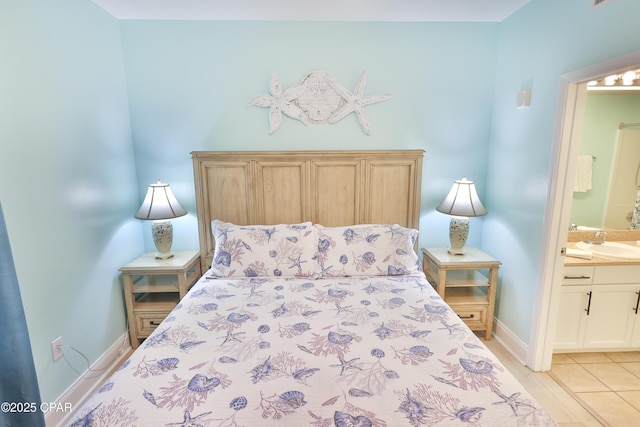 bedroom with a sink, light tile patterned floors, baseboards, and connected bathroom