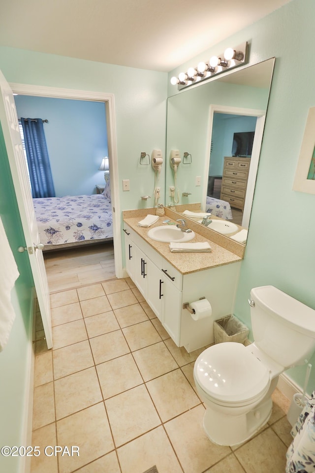 ensuite bathroom featuring toilet, ensuite bath, vanity, and tile patterned flooring