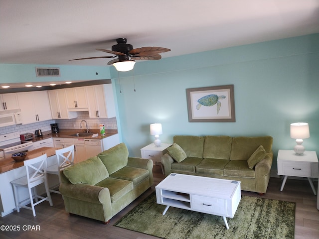 living area with dark wood-style floors, ceiling fan, and visible vents