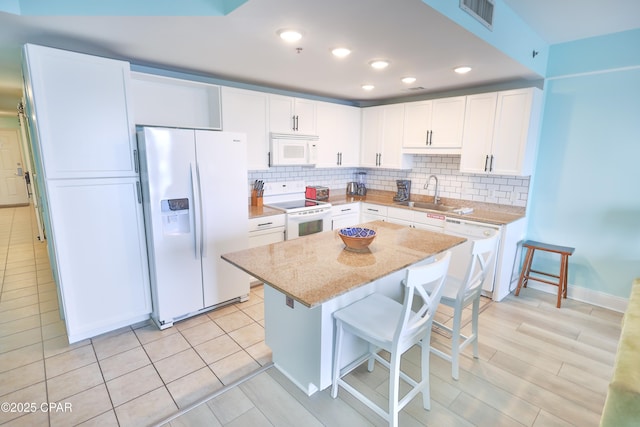 kitchen featuring white appliances, tasteful backsplash, visible vents, and a sink
