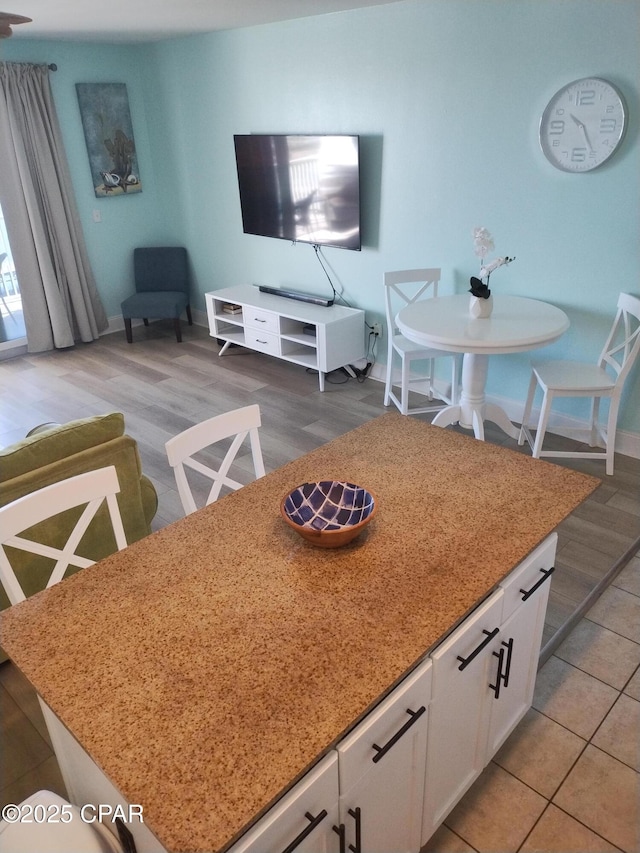 interior space featuring light stone counters, a center island, light wood-style floors, and white cabinets