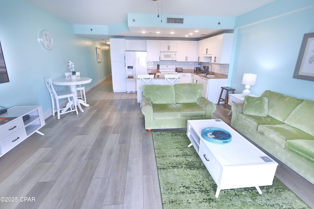 living room featuring light wood-style flooring, recessed lighting, baseboards, and visible vents