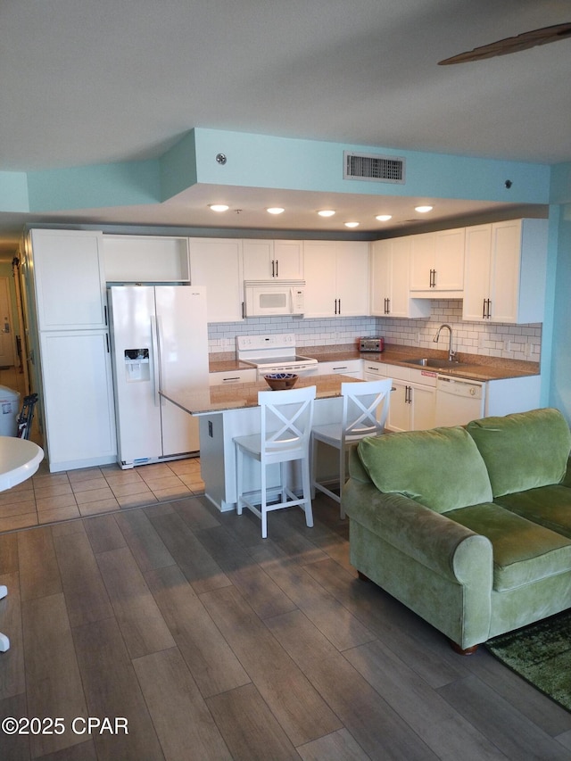 kitchen with white appliances, visible vents, white cabinets, a sink, and backsplash