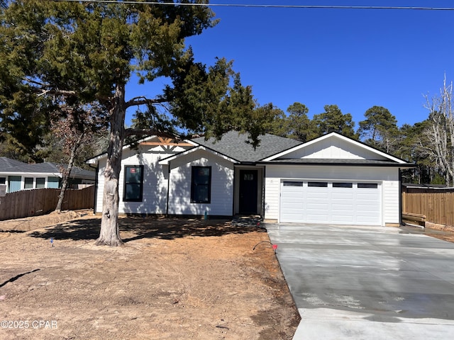 view of front of house featuring a garage, driveway, roof with shingles, and fence