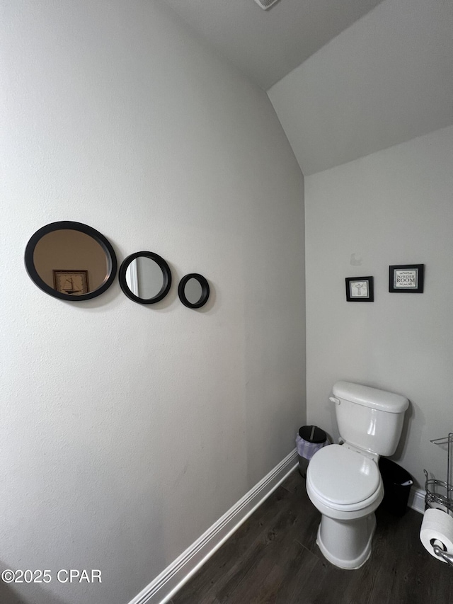 bathroom featuring lofted ceiling, toilet, baseboards, and wood finished floors