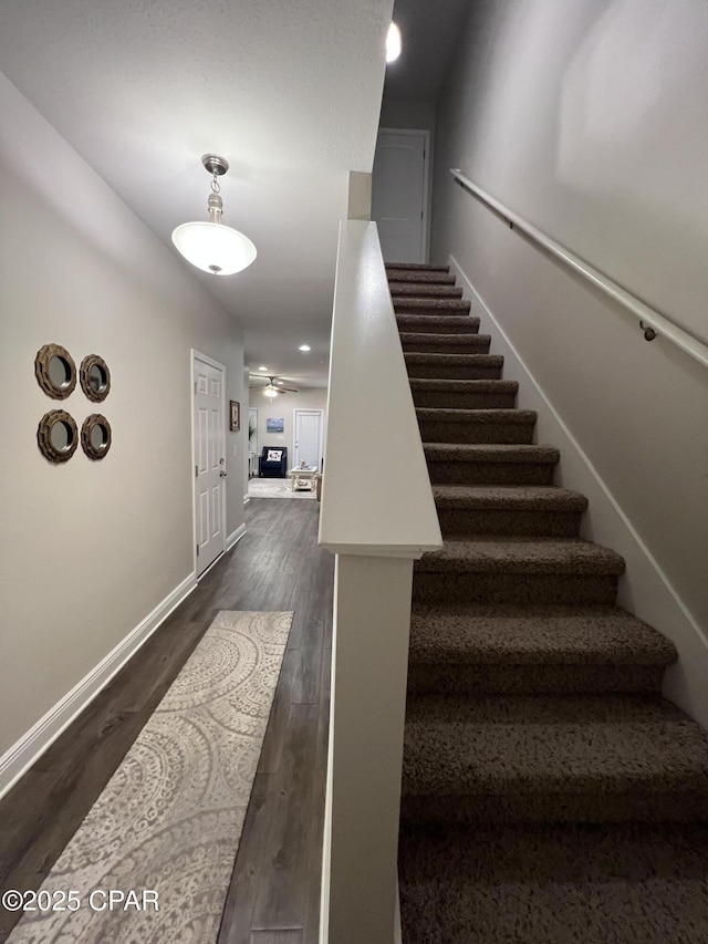 stairway with ceiling fan, wood finished floors, and baseboards