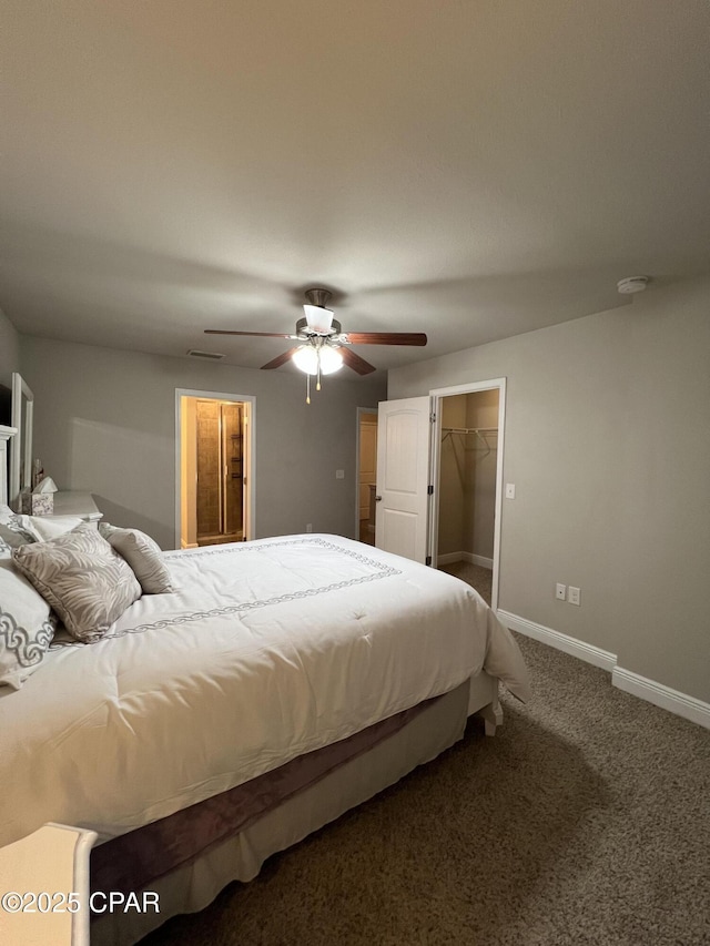 bedroom with ceiling fan, baseboards, a walk in closet, and carpet flooring