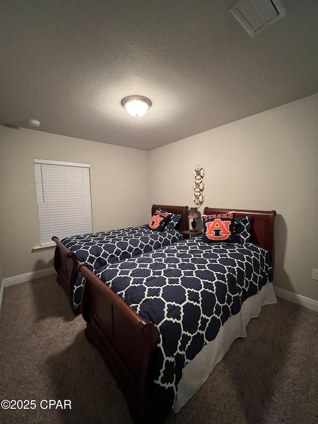 carpeted bedroom with visible vents, a textured ceiling, and baseboards