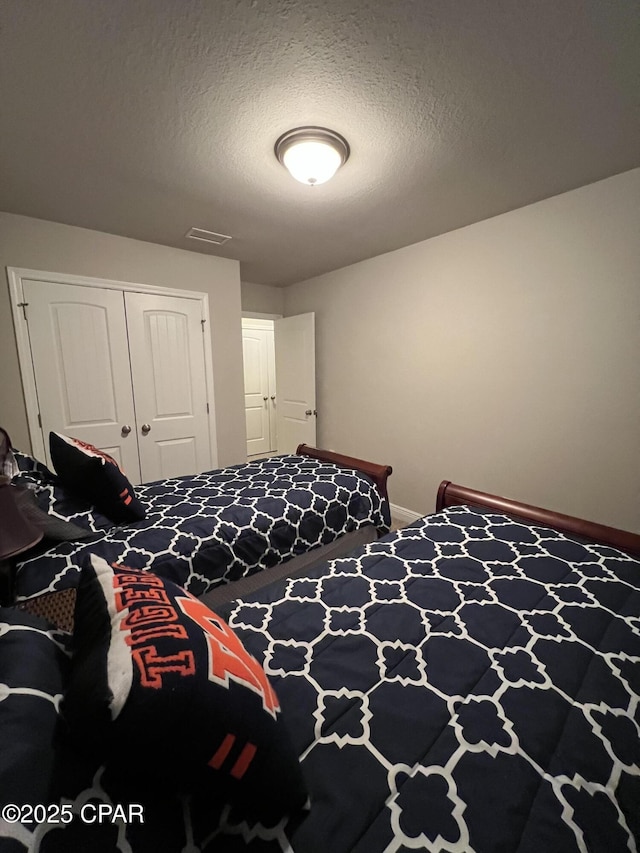 bedroom featuring baseboards, a textured ceiling, visible vents, and a closet