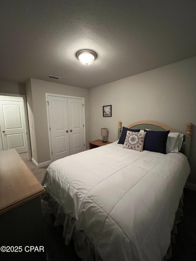 bedroom featuring a textured ceiling, carpet floors, visible vents, baseboards, and a closet