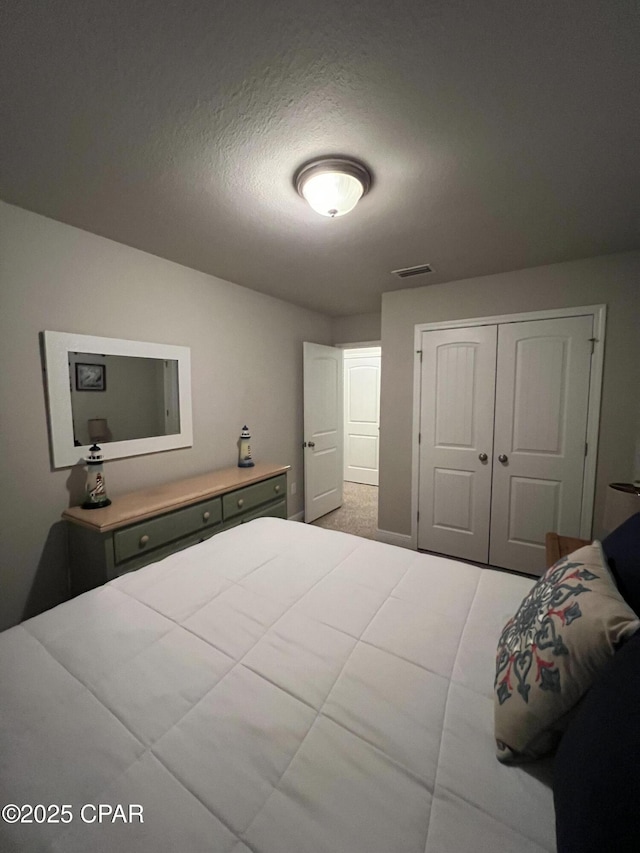 bedroom with a textured ceiling, visible vents, and a closet