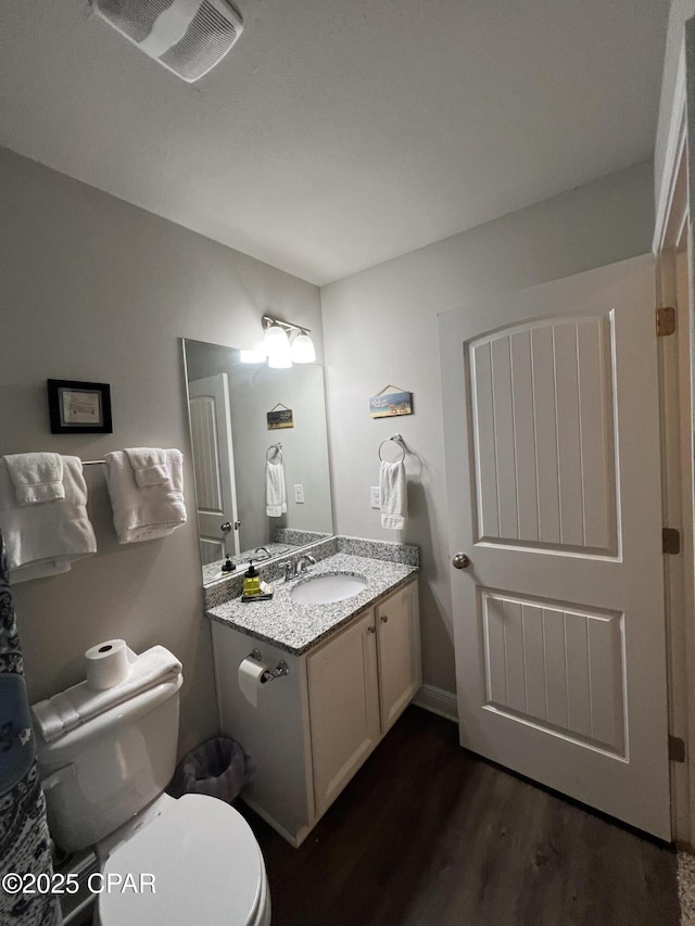 bathroom featuring visible vents, vanity, toilet, and wood finished floors