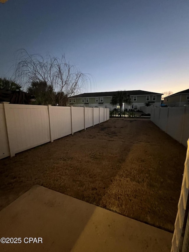 yard at dusk featuring a fenced backyard