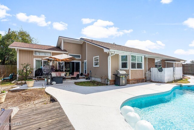 rear view of property with a fenced in pool, outdoor lounge area, fence, and a patio