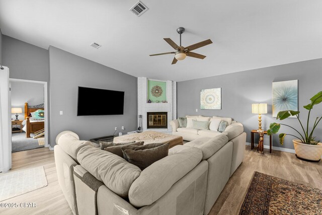 living room featuring light wood-type flooring, visible vents, and vaulted ceiling