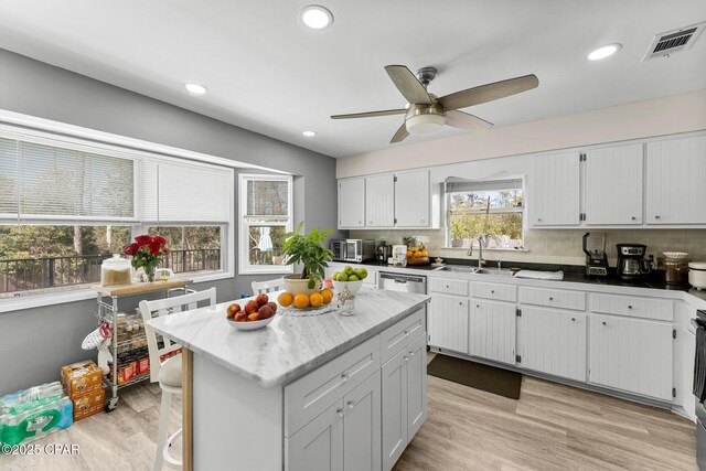 kitchen with tasteful backsplash, a sink, visible vents, and light wood-style floors