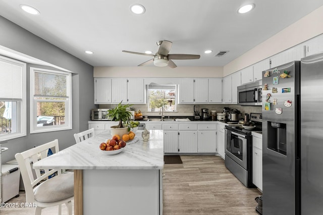 kitchen featuring visible vents, stainless steel appliances, light wood-type flooring, and white cabinetry