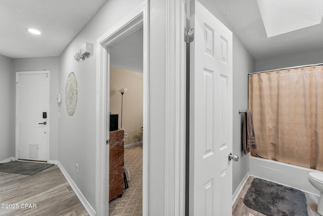 full bath with shower / bath combo, wood finished floors, toilet, and baseboards