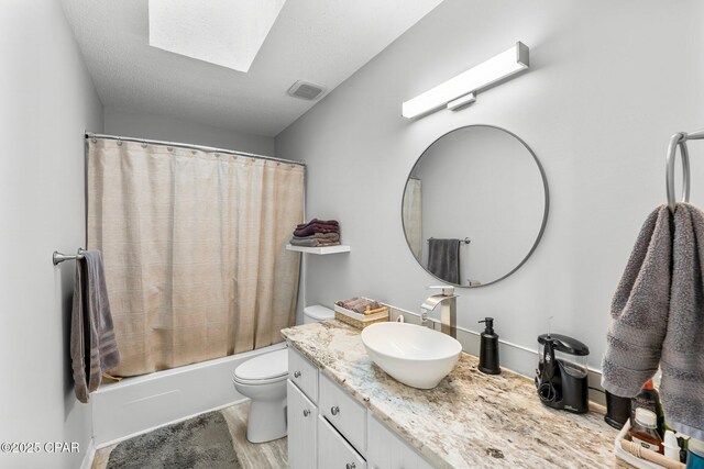 full bathroom featuring a skylight, visible vents, toilet, vanity, and wood finished floors