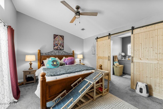 carpeted bedroom with lofted ceiling, ceiling fan, a barn door, and visible vents