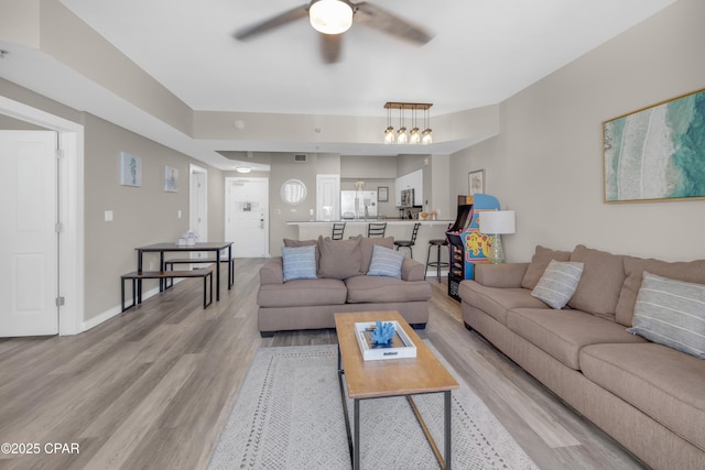 living area with ceiling fan, baseboards, visible vents, and light wood-style floors