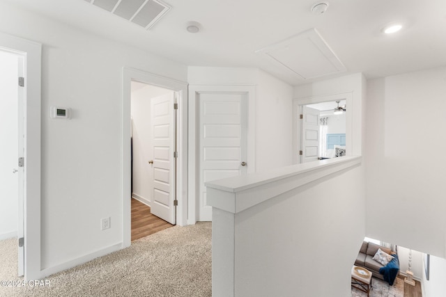 hallway featuring light carpet, baseboards, and visible vents