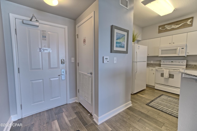 kitchen with white appliances, white cabinetry, visible vents, and wood finished floors