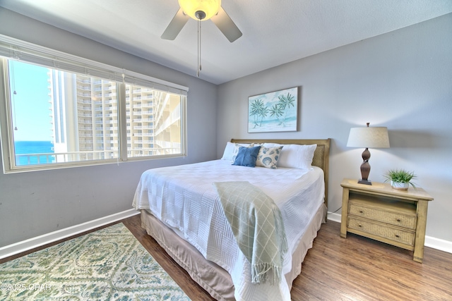 bedroom with ceiling fan, baseboards, and wood finished floors