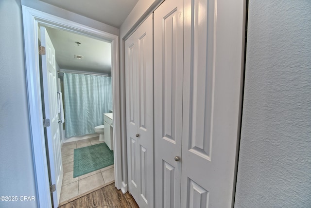 corridor featuring visible vents, a textured wall, and tile patterned floors