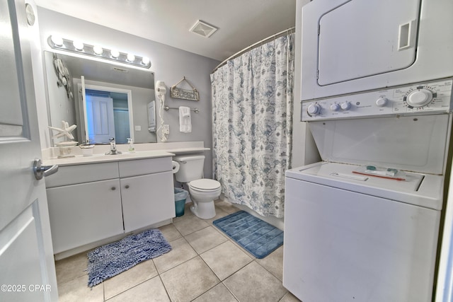 bathroom featuring visible vents, toilet, stacked washer / drying machine, tile patterned flooring, and vanity