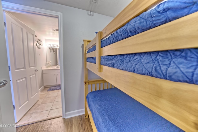 tiled bedroom featuring ensuite bath and baseboards