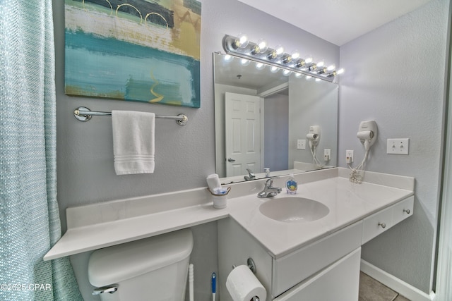 bathroom with a textured wall, vanity, and toilet