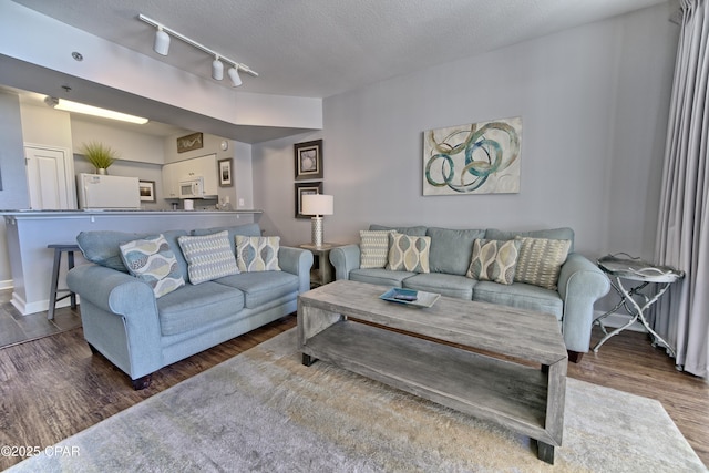 living area featuring a textured ceiling, track lighting, and wood finished floors