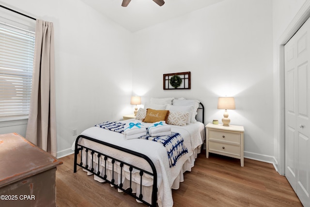 bedroom featuring a closet, wood finished floors, a ceiling fan, and baseboards