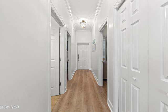 hallway with light wood finished floors, baseboards, and ornamental molding