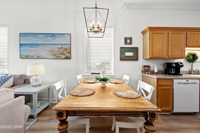 dining area featuring a chandelier, light wood finished floors, and crown molding