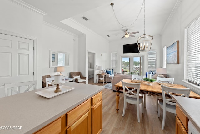 dining space with a notable chandelier, visible vents, french doors, light wood-type flooring, and crown molding