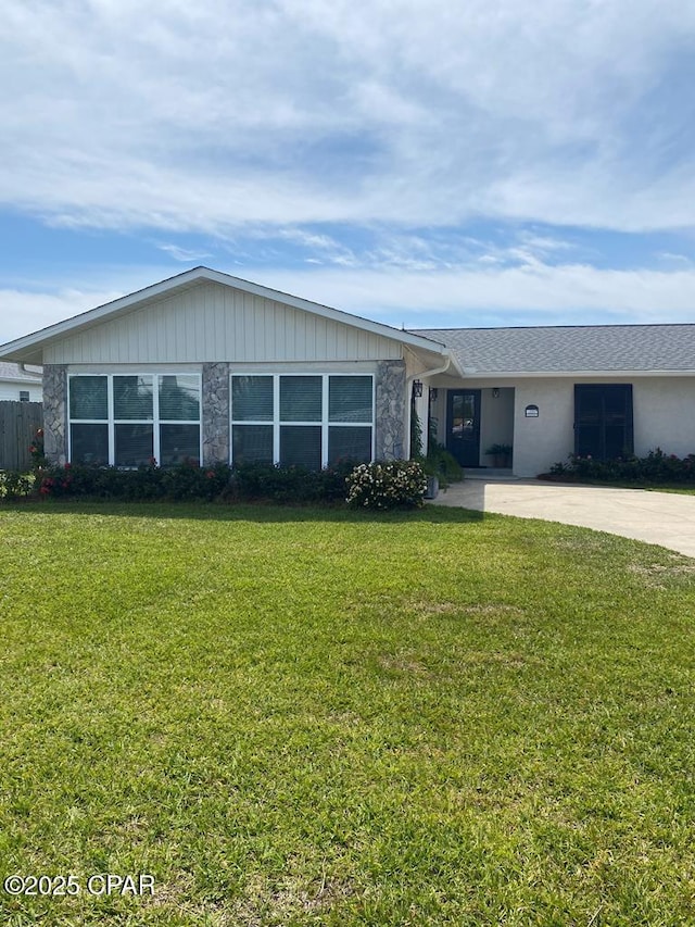 single story home with stone siding, a front lawn, and concrete driveway