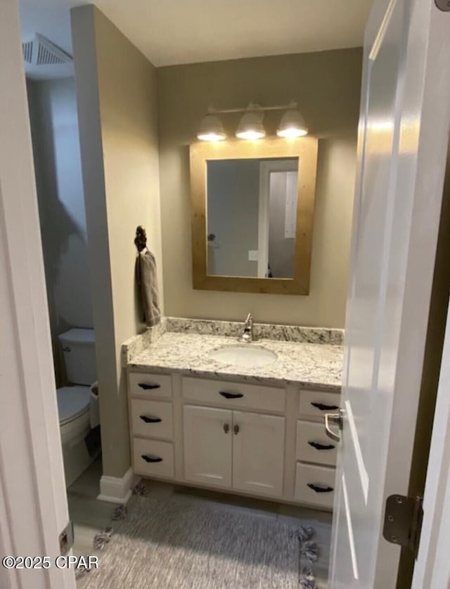 half bathroom with toilet, visible vents, and vanity