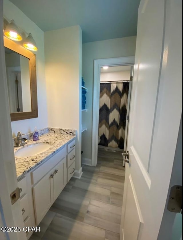 bathroom featuring toilet, curtained shower, wood finished floors, and vanity