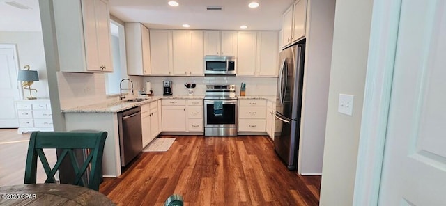 kitchen featuring visible vents, appliances with stainless steel finishes, dark wood-style flooring, a sink, and backsplash